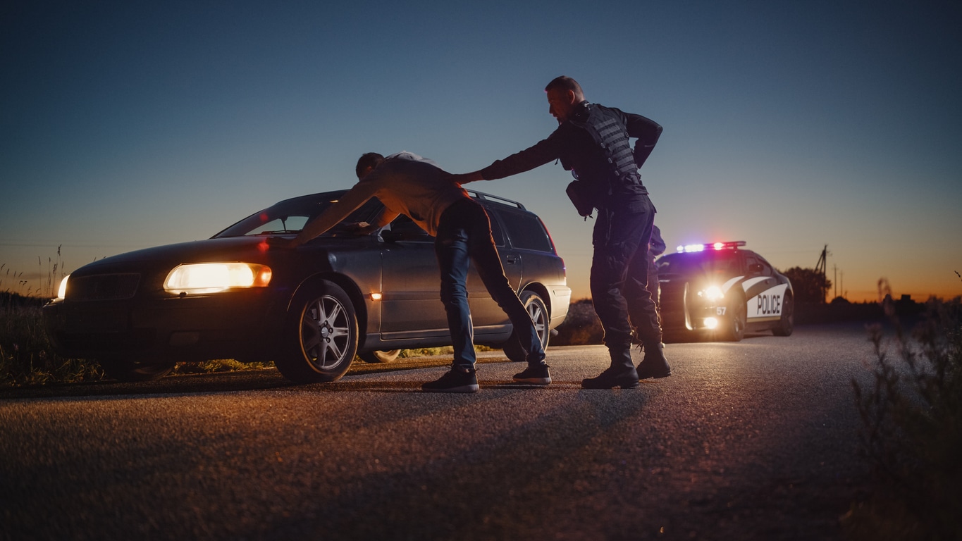 Police officer puts man up against car